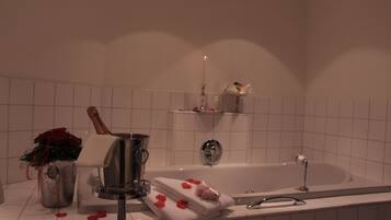 A bathroom with a bathtub, a shower, a vanity with a mirror, and a towel rack.