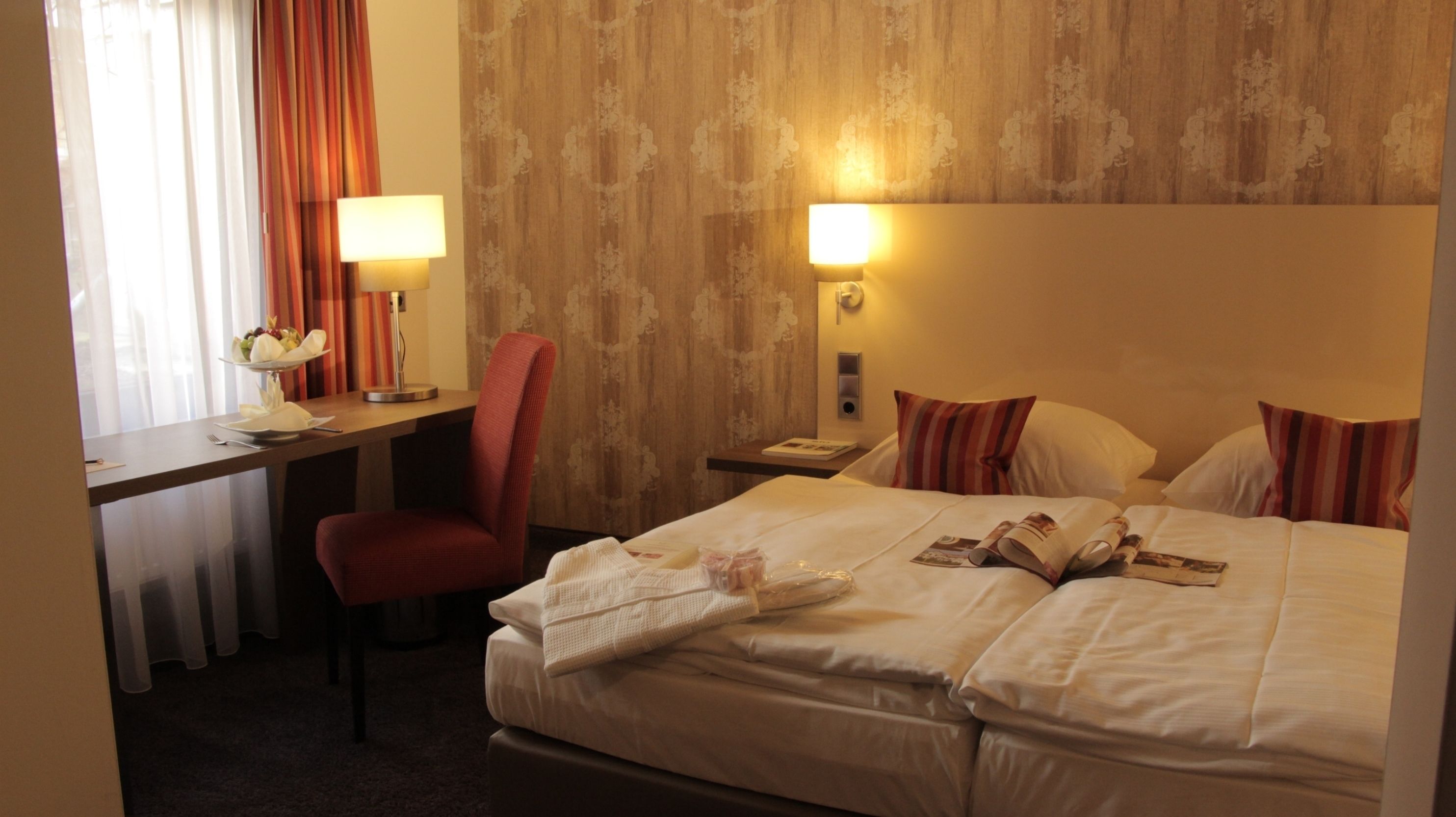 A hotel room with a bed, a desk, a chair, and a nightstand.