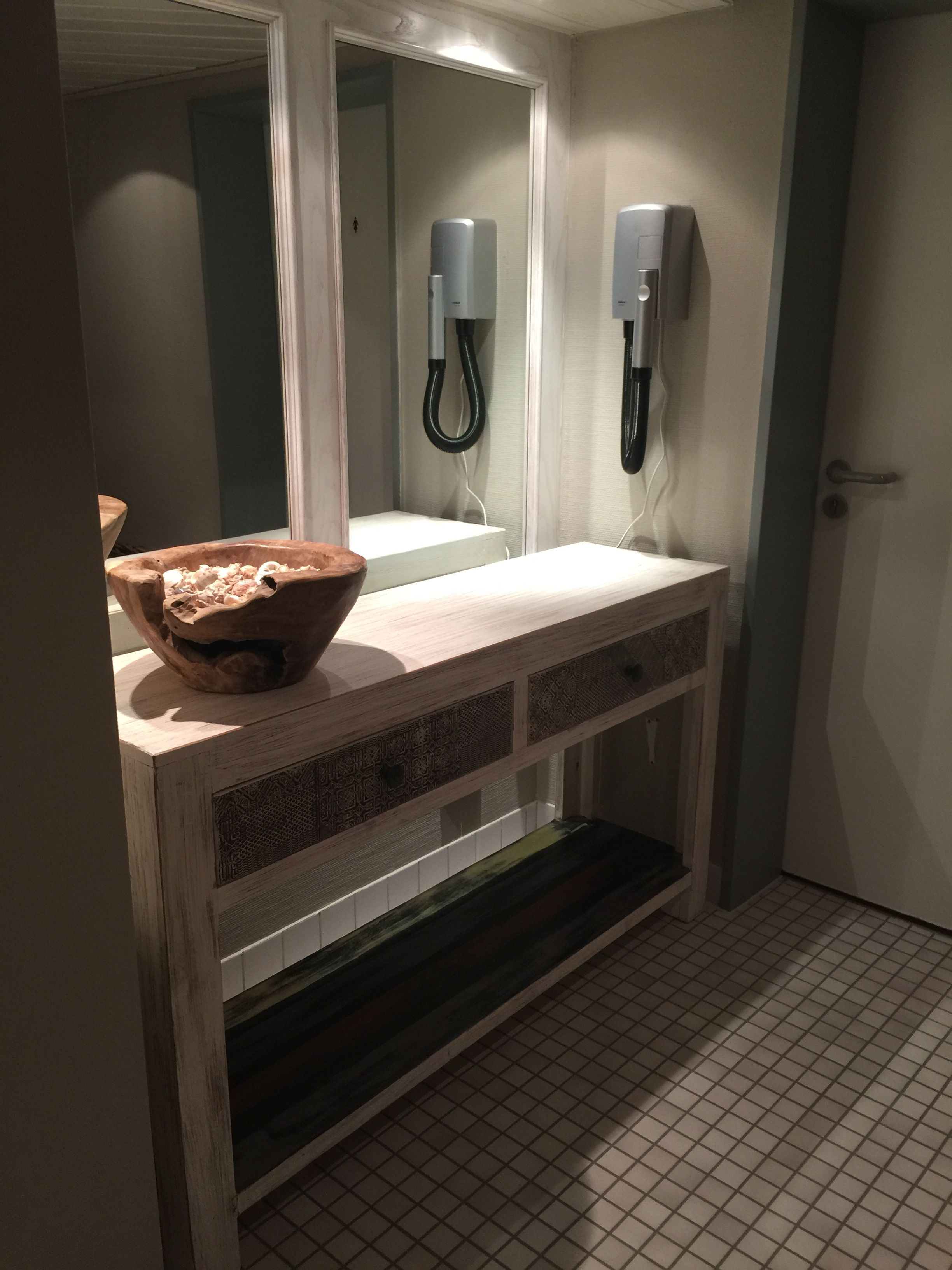 Un baño con tocador de madera, un espejo grande y un perchero para toallas.