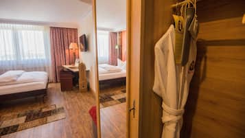 A hotel room with two beds, a desk, a chair, and a TV on the wall.