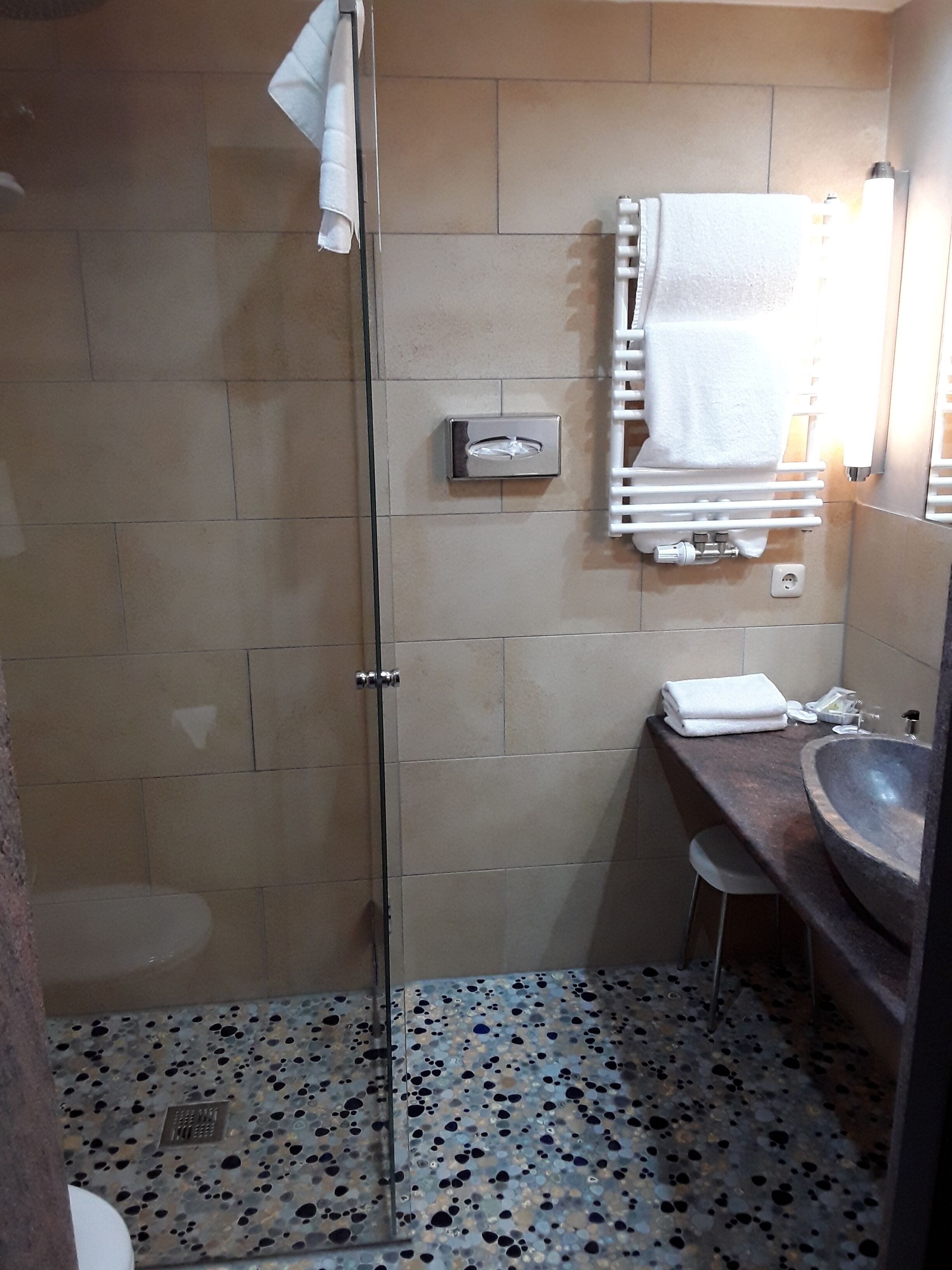 A bathroom with a shower, a sink, and a towel rack.