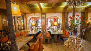 Un restaurante con mesas y bancos de madera, una araña y un florero decorativo con flores.