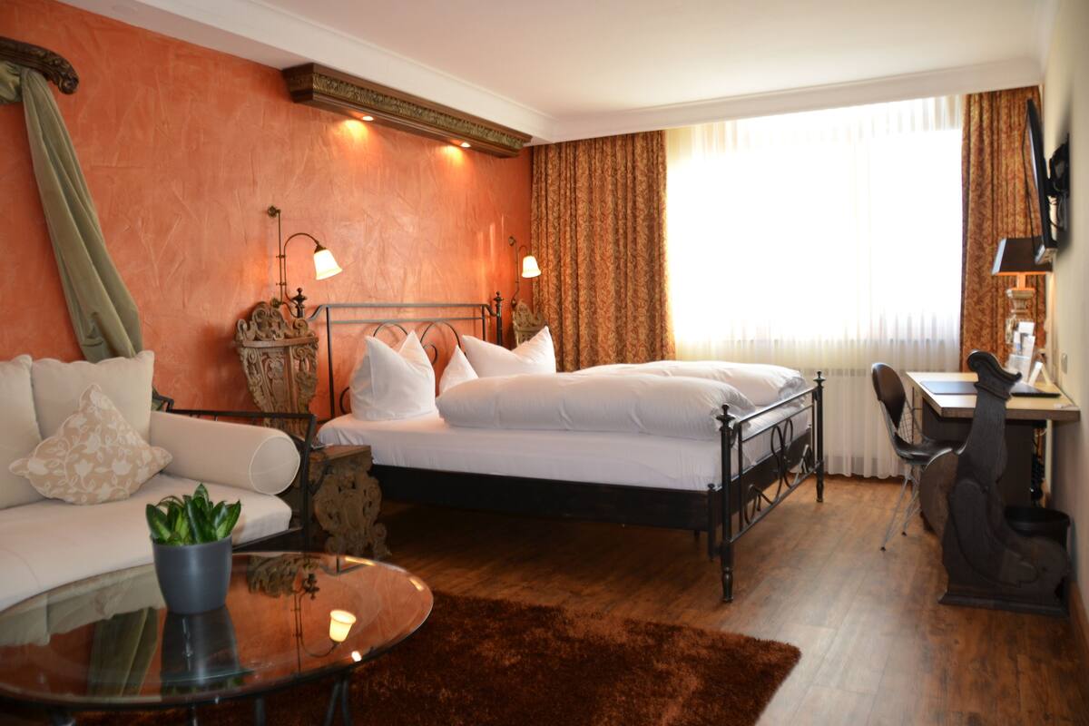 Een hotelkamer met een bed, een bureau, een stoel, een bank en een kleine tafel met een plant.