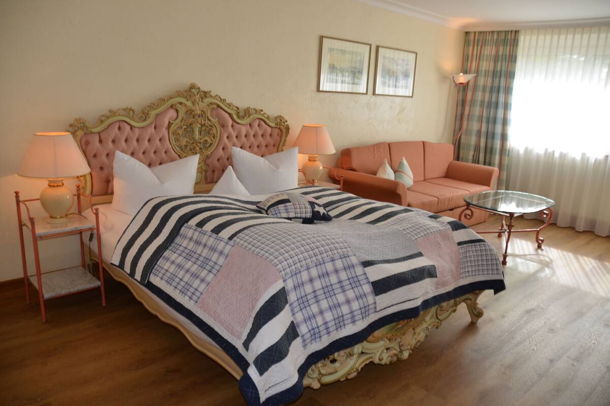 Een slaapkamer met een groot bed, twee nachtkastjes, een bank en een glazen tafel.