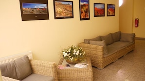 A reception area with wicker furniture, a vase of flowers, and framed landscape pictures on the wall. - Bed & Breakfast zum alten Ratskeller (Vetschau/Spreewald)