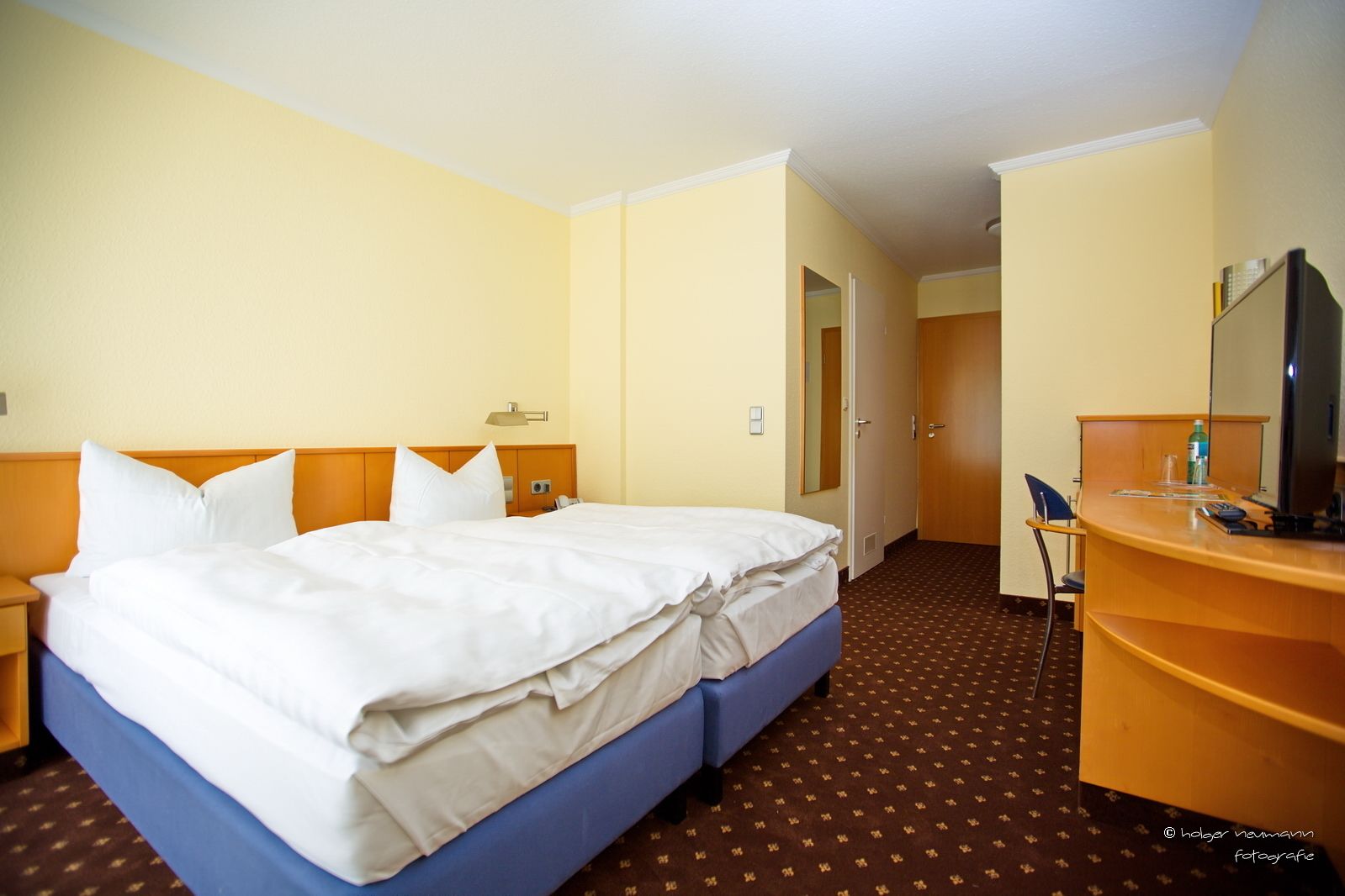 Una habitación de hotel con una cama, un escritorio, una silla y un televisor.