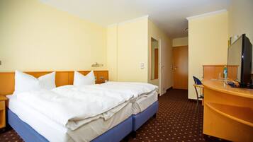 Una habitación de hotel con una cama, un escritorio, una silla y un televisor.