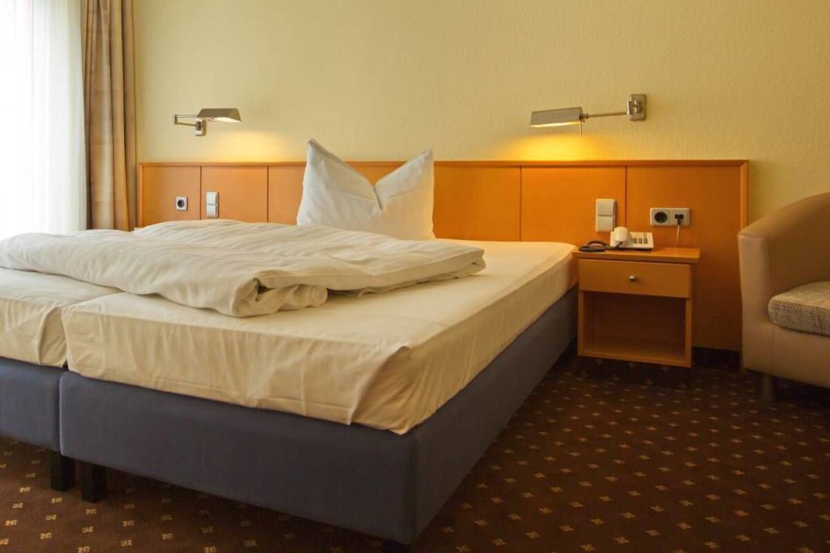 Une chambre d’hôtel avec un lit, une table de chevet, une lampe et une chaise.
