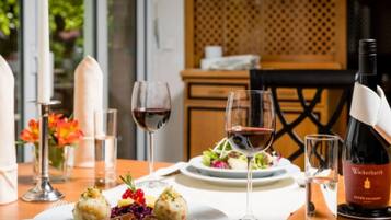 A dining table with plates of food, wine glasses, and a bottle of Wackerbarth wine.