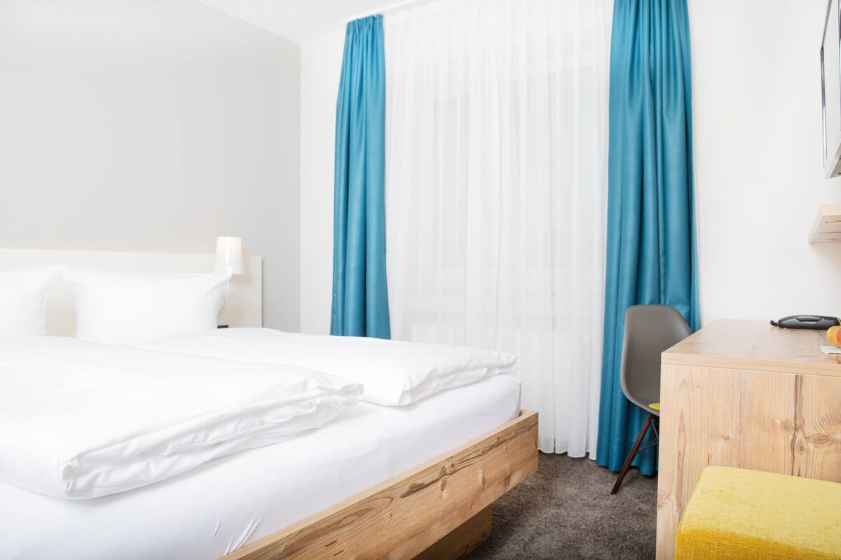 A hotel room with a wooden bed frame, a desk, and a chair.