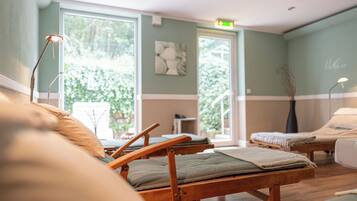 A room with two wooden beds, a small table, and a chair.