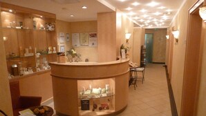 Zona de recepción con mostrador curvo, vitrinas de vidrio y un área de descanso con dos sillas.