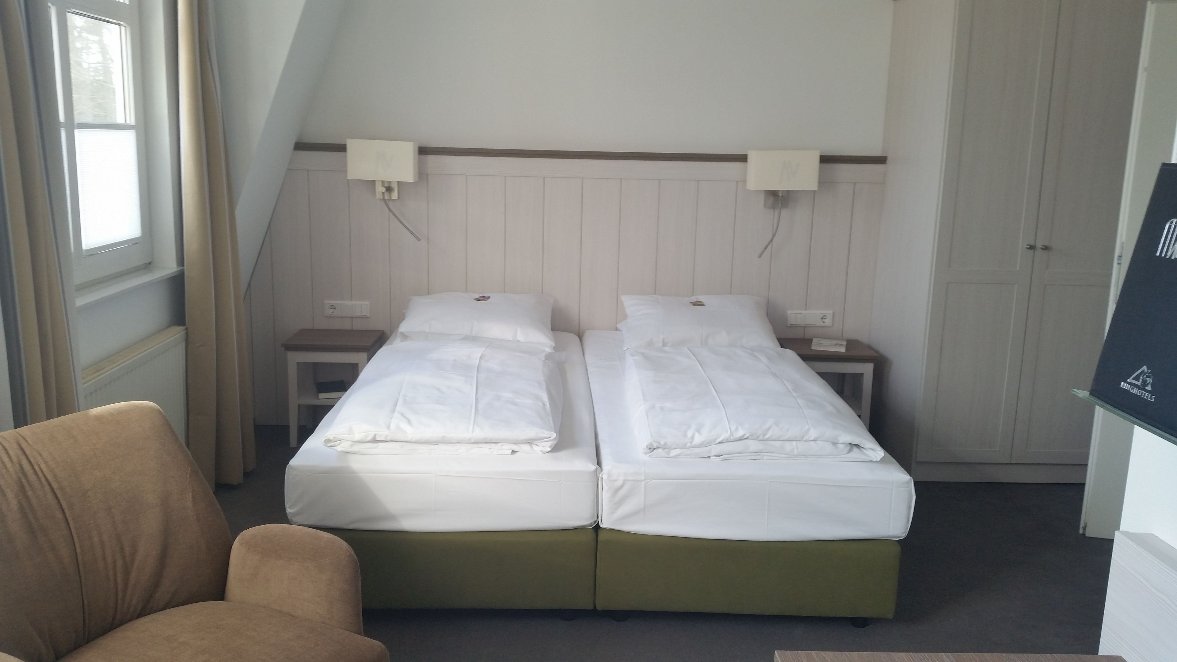 A twin room with two single beds, a small table, a chair, and a wardrobe.