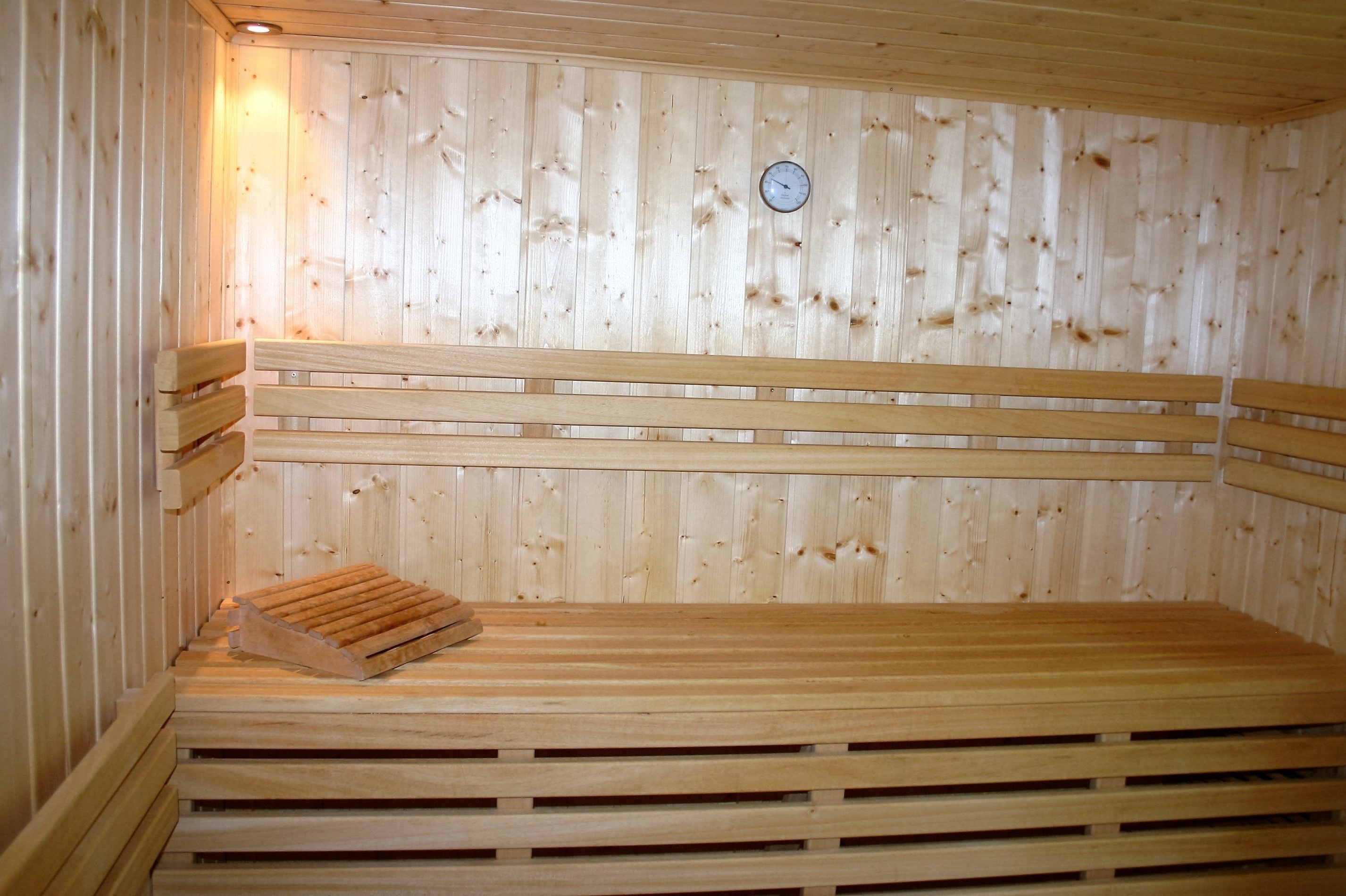 Un sauna en bois avec des bancs et une horloge au mur.
