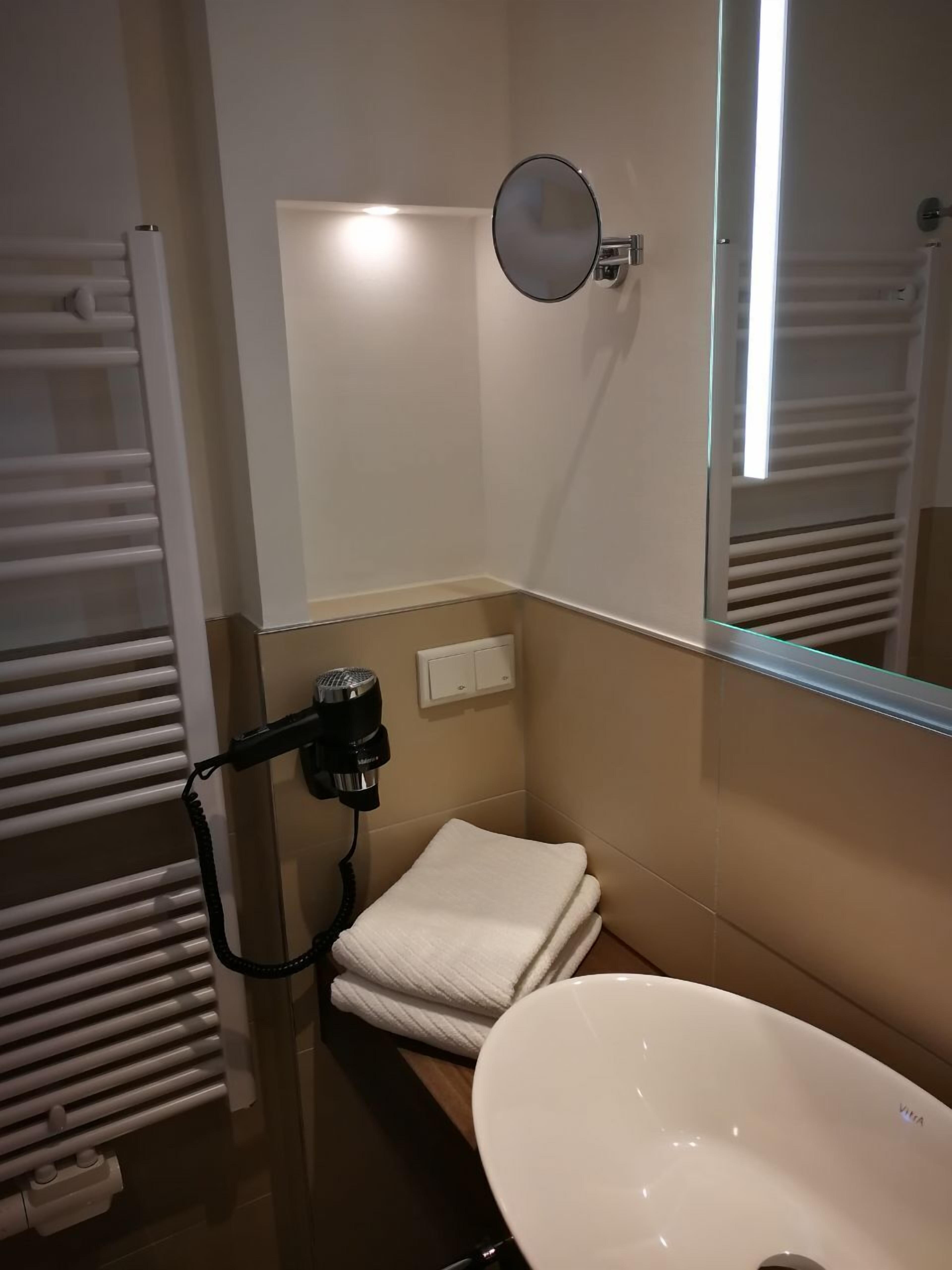 A bathroom with a white sink, a towel rack, a hairdryer, and a mirror.