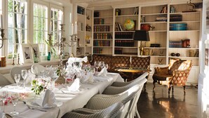 A dining room with a long table set for a meal, surrounded by bookshelves filled with books and decorative items.