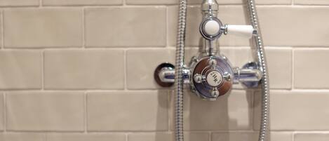 Une salle de bain avec un mur carrelé et un dispositif de douche équipé d’un pommeau de douche à main.