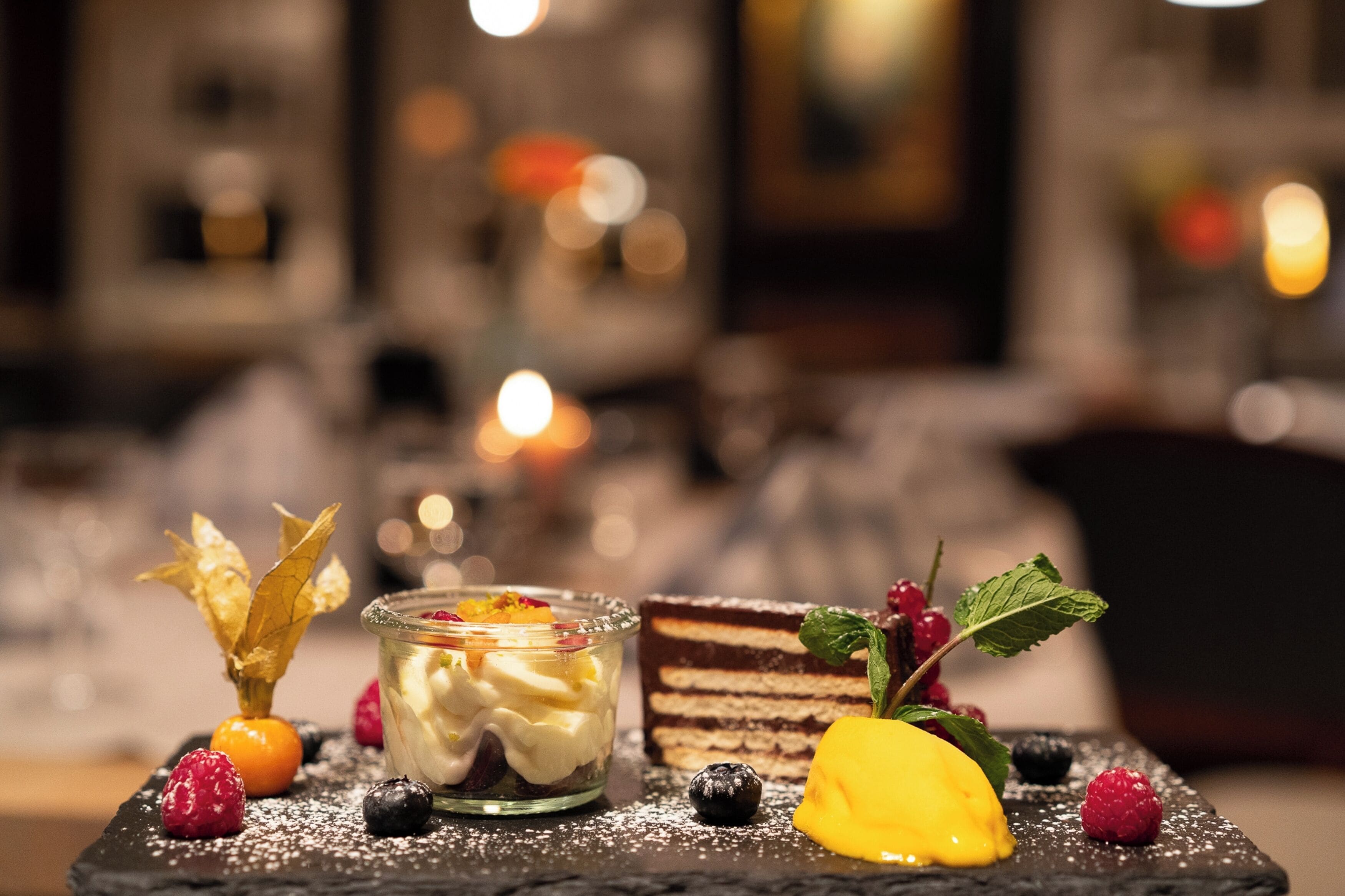 A dessert with fruit and leaves on a slate plate.