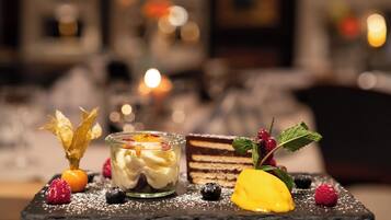 A dessert with fruit and leaves on a slate plate.