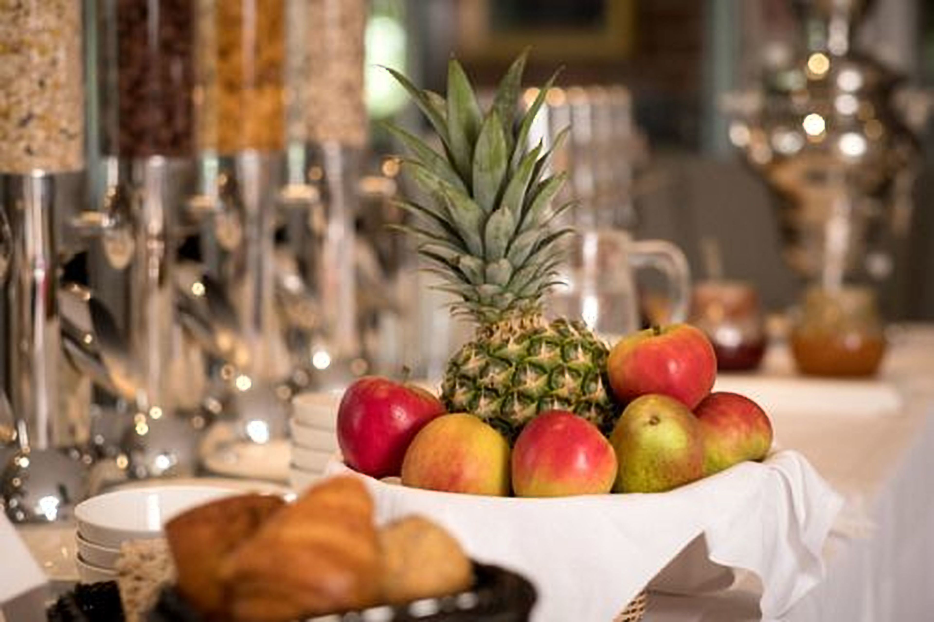 A breakfast buffet with fruits, pastries, and a pineapple centerpiece.