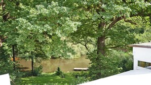 A river with a wooden dock, surrounded by dense green foliage and trees.