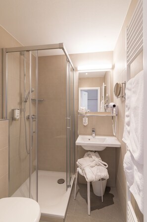 A modern bathroom with a glass shower enclosure, a sink, a toilet, and a towel rack. - Hotel Adler Post (Schwetzingen)