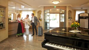 Un área de recepción con un piano de cola, mostrador de recepción y un letrero.