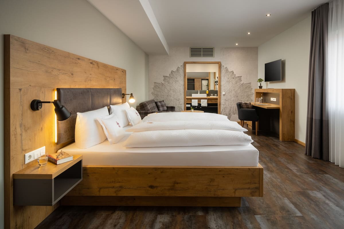 Una habitación de hotel moderna con una cama grande, un escritorio, un espejo y una televisión.