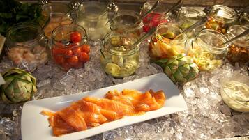 Een buffet met diverse etenswaren op ijs, waaronder zalm, groenten en dipsauzen.
