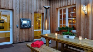 A wooden exterior with a reception area, a payment kiosk, and a bench with towels. - Ringhotel Landhaus Gardels (Sankt Michaelisdonn)