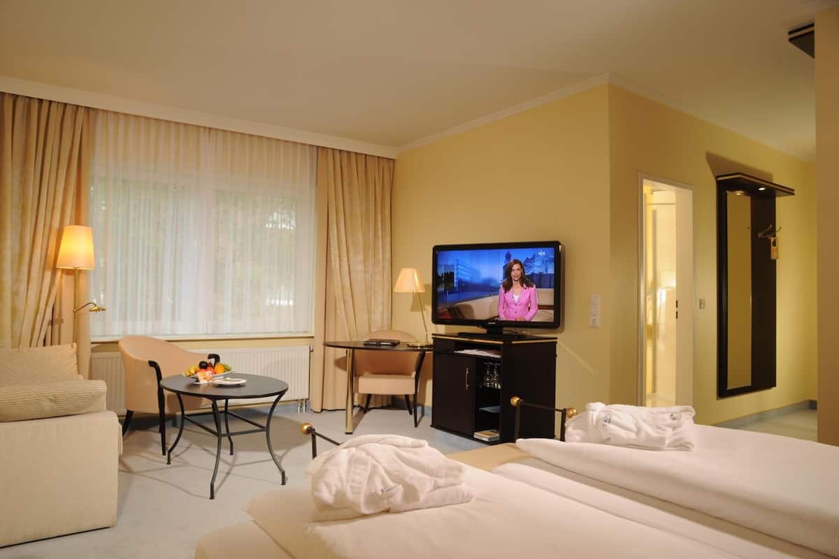 Ein Hotelzimmer mit Bett, Fernseher, Schreibtisch und Stuhl.