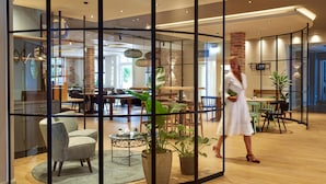 A modern interior with a glass partition, wooden flooring, and indoor plants. - Ringhotel Landhaus Gardels (Sankt Michaelisdonn)