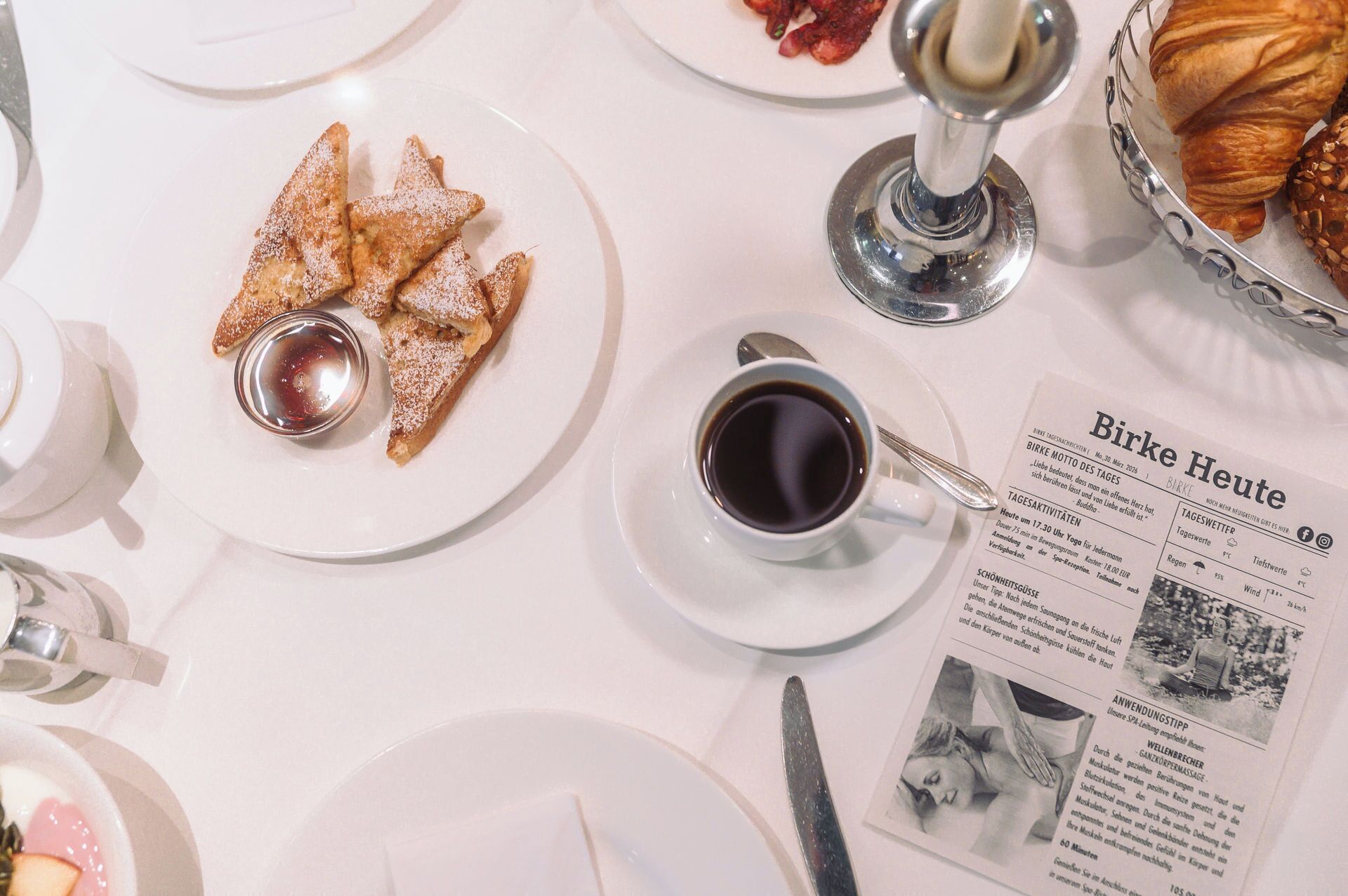 Ein Frühstückstisch mit Gebäck, einer Kaffeetasse und einer Speisekarte.