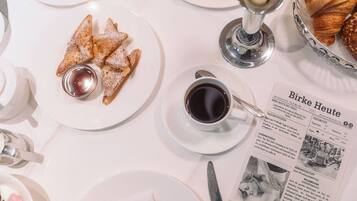 Ein Frühstückstisch mit Gebäck, einer Kaffeetasse und einer Speisekarte.