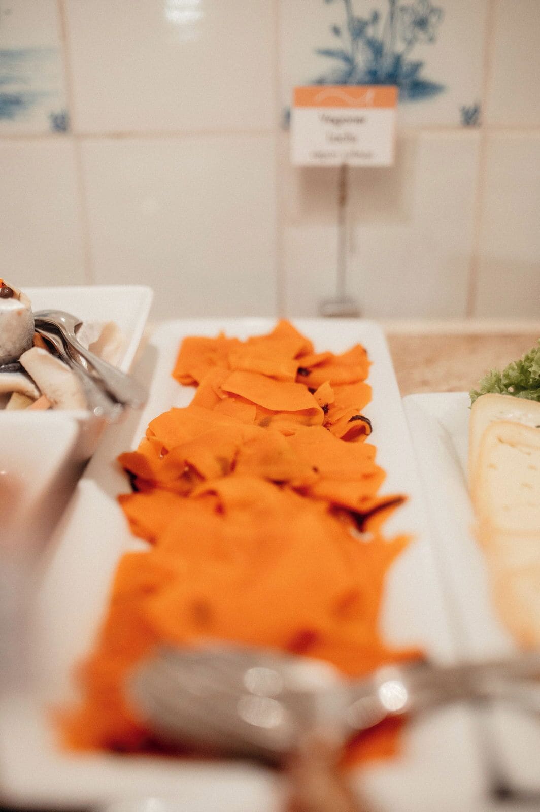 A buffet with various food items including orange slices and a dish with a creamy sauce.
