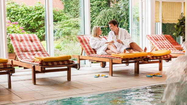 Zona de piscina con sillones reclinables y una alberca.