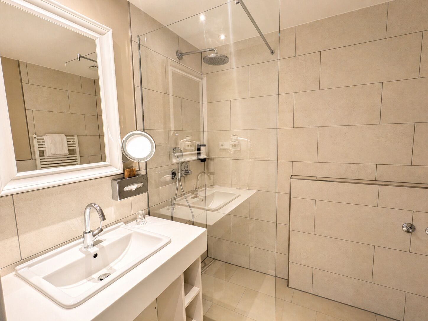 A modern bathroom with a glass-enclosed shower, a double sink vanity, and a large mirror.