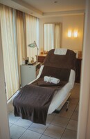 Una habitación de hotel con cama, mesita de noche, lámpara, espejo y cortinas.