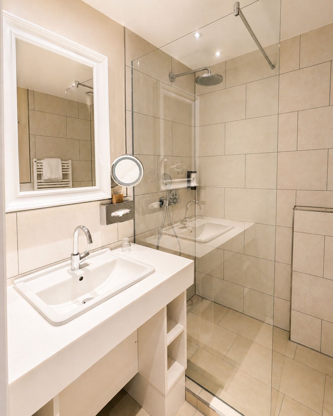 Un baño moderno con dos lavamanos, cabina de ducha de vidrio y un espejo grande.