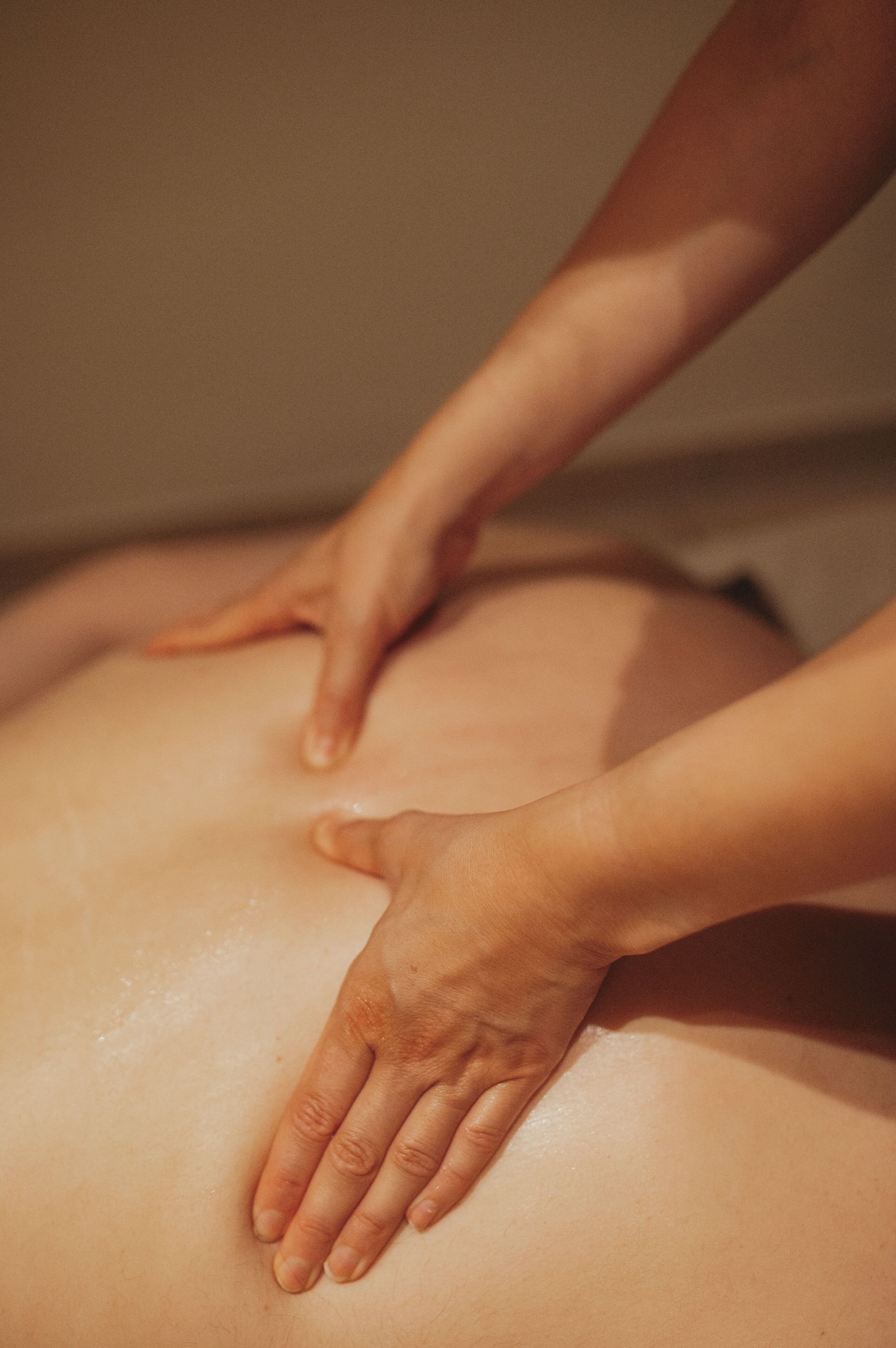 A close-up of hands performing a massage on a person's back.