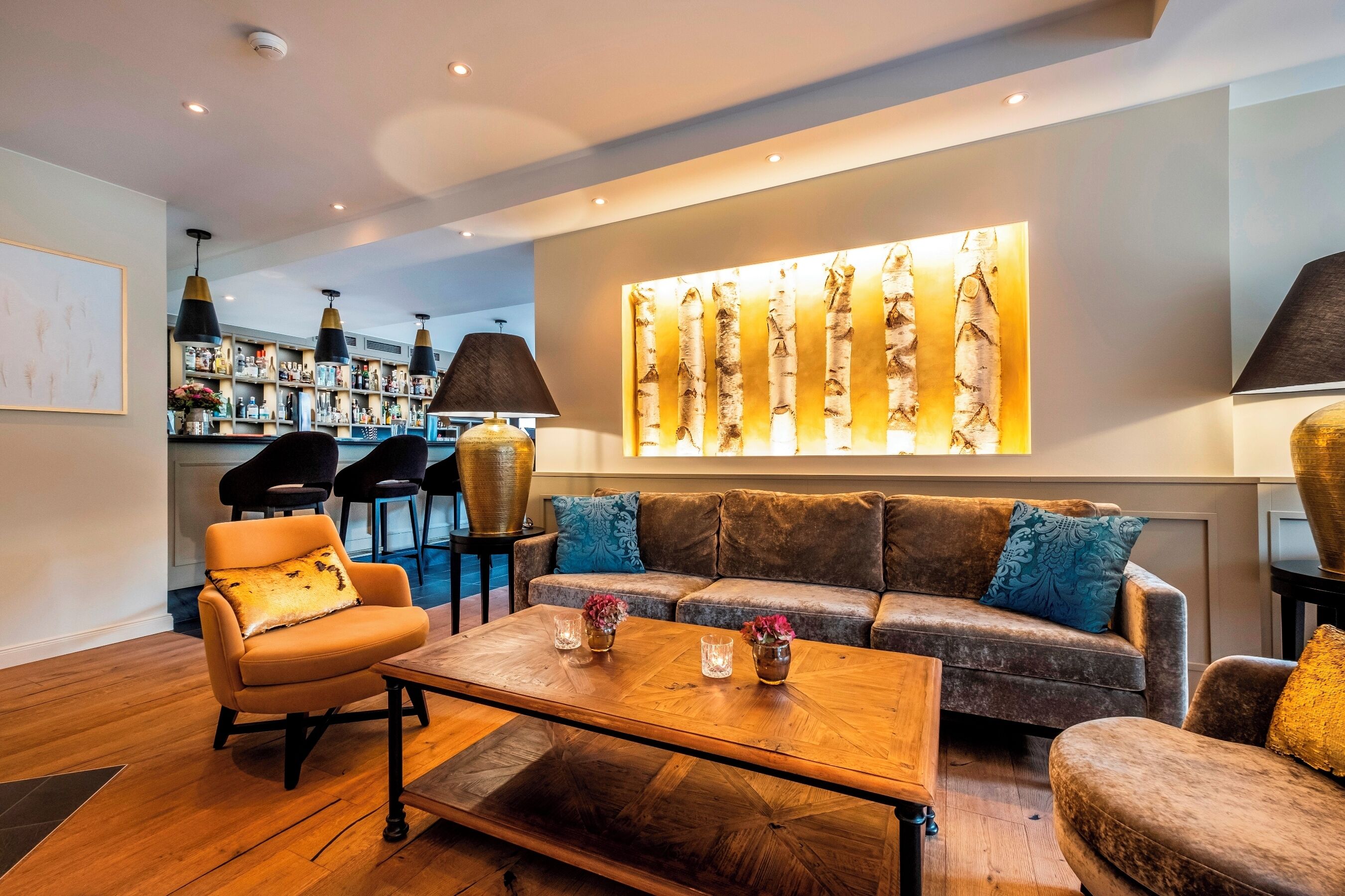 Uma área de estar moderna com um sofá, poltronas, uma mesa de centro e um bar com prateleiras cheias de garrafas.