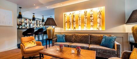 Uma área de estar moderna com um sofá, poltronas, uma mesa de centro e um bar com prateleiras cheias de garrafas.