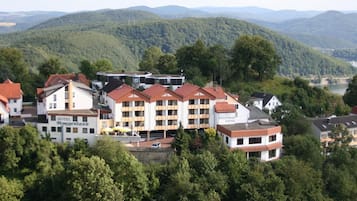 A hotel complex with multiple buildings, surrounded by lush greenery and hills.