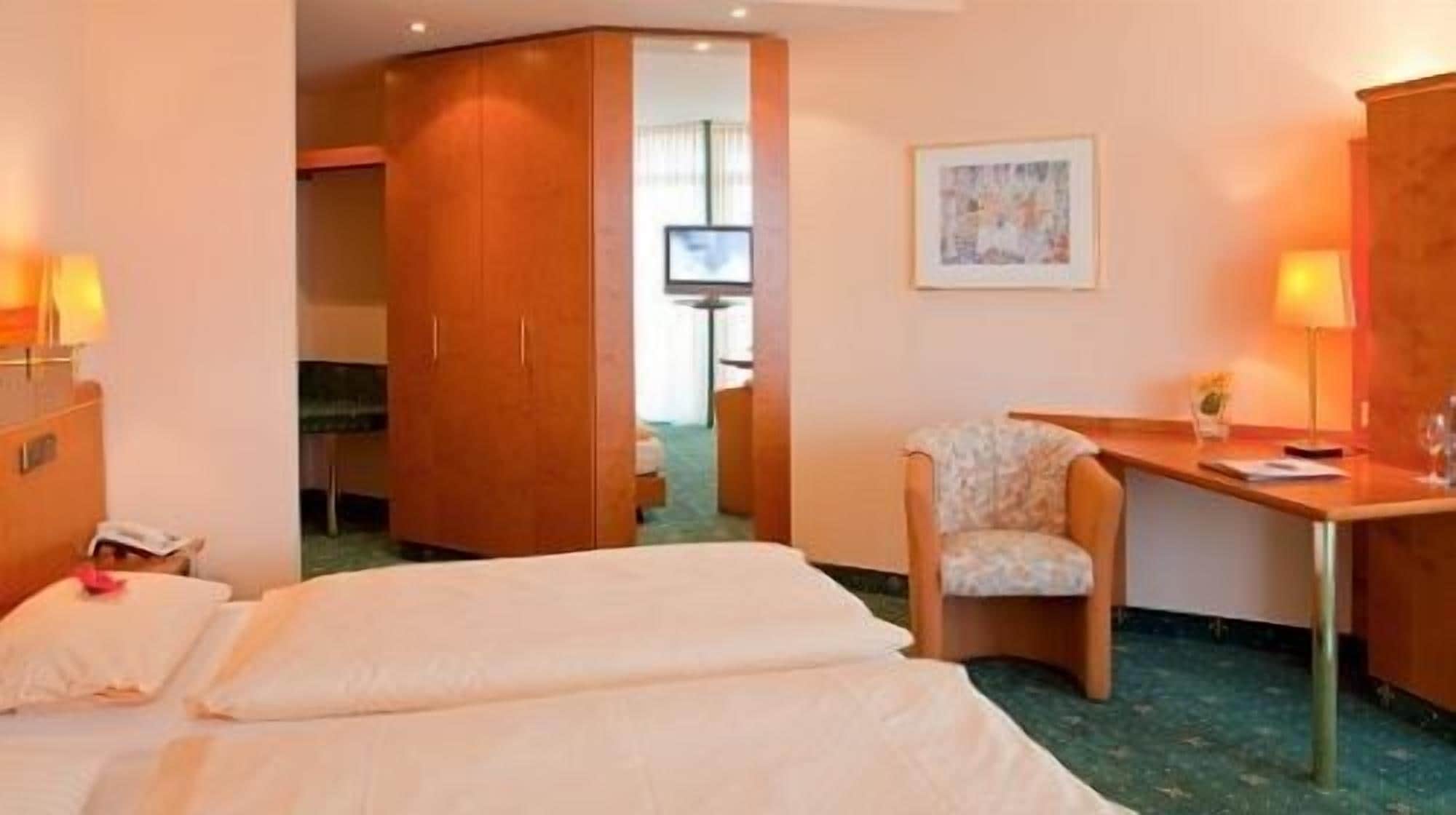 Una habitación de hotel con cama, escritorio, silla y televisión.