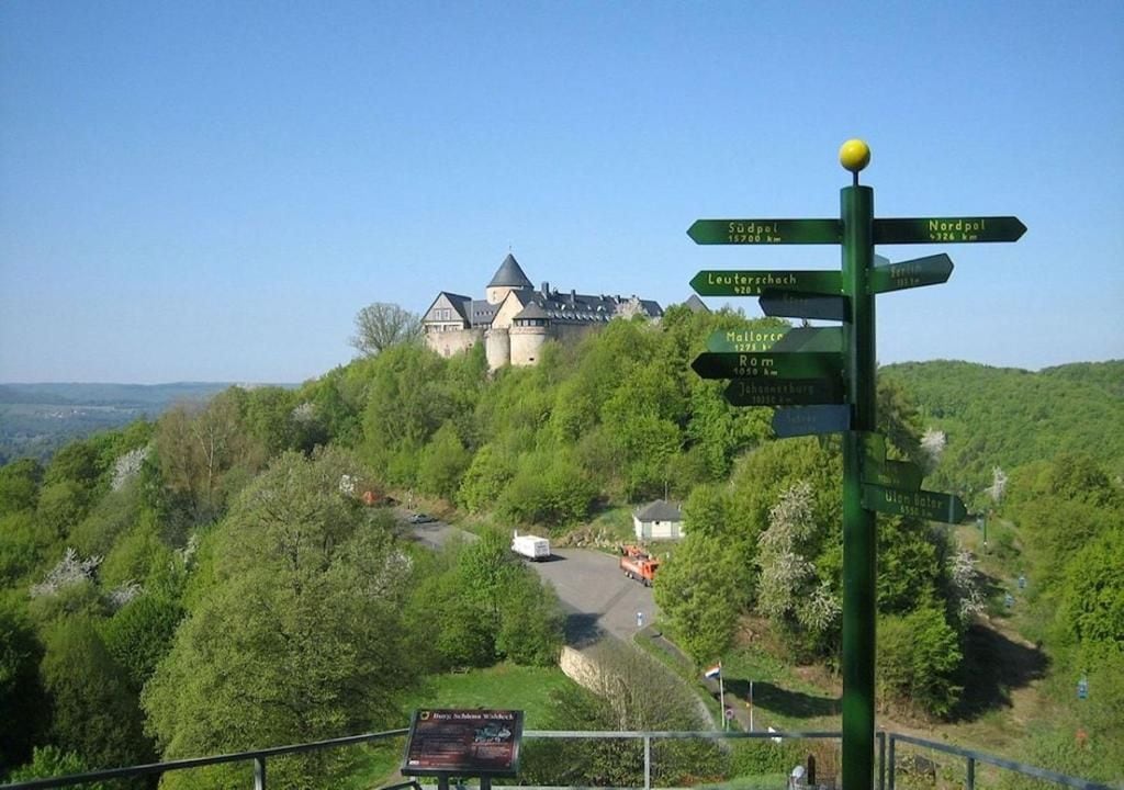 A castle on a hill with a directional signpost.