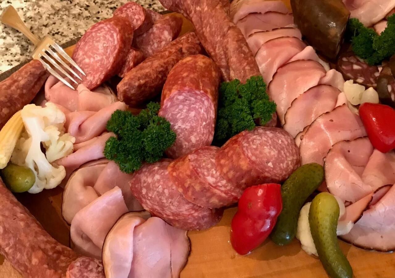 A charcuterie board with various meats, olives, and vegetables.