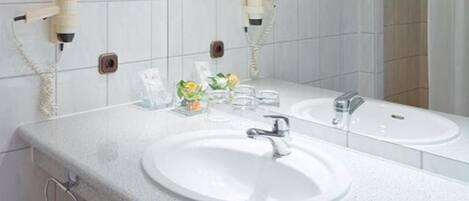 A modern bathroom with two sinks, a large mirror, and a shower area.