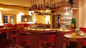 A bar area with multiple seating options, including bar stools and a high bar counter with a wine rack. - Ringhotel Roggenland (Waldeck)