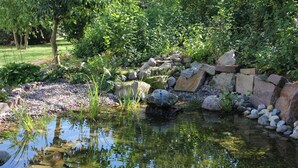 A tranquil garden pond with a stone wall and lush greenery. - Waldhotel Schäferberg (Espenau)