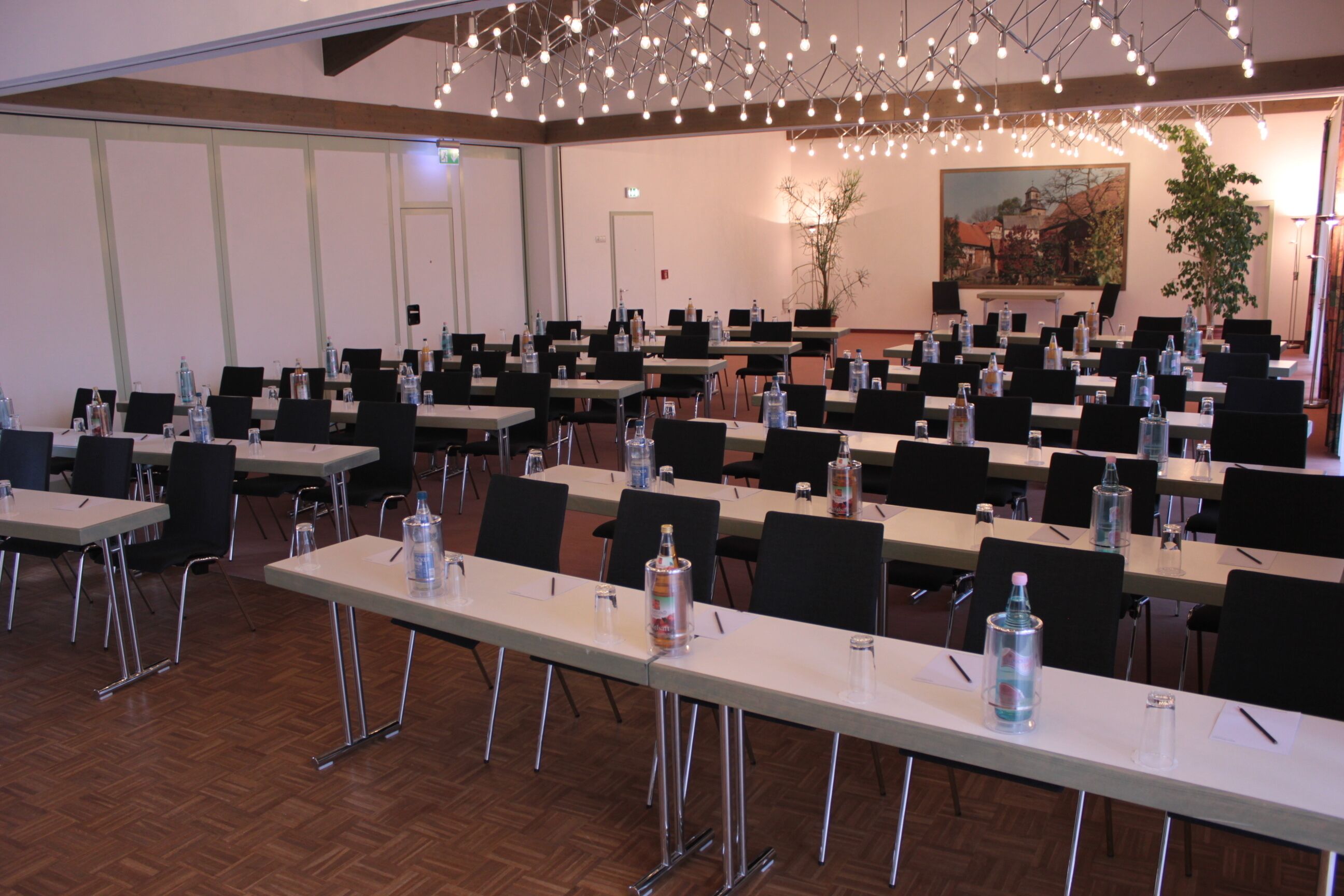 Una sala conferenze con diversi tavoli, sedie e bottiglie d'acqua.